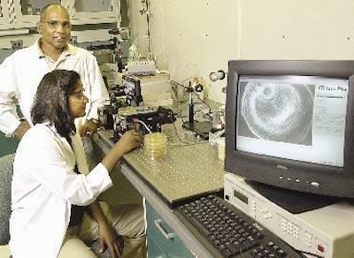 Arun Bhunia (standing) and Padmapriya Banada use a laser and a computer monitor to observe scatter patterns in a Petri dish in their Purdue University lab.