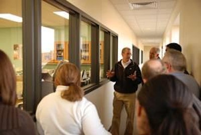 From the outside observation hallway, Joseph Schultz explains the lab operations to a group of visitors during the open house.
