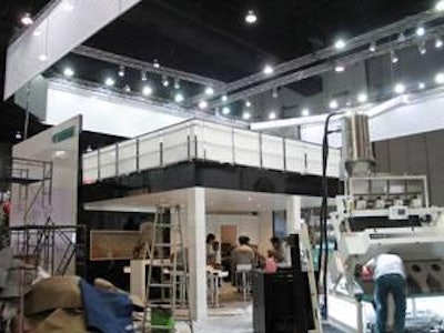 Workers put the finishing touches on the Bühler exhibit at Victam Asia. The exhibit is one of the largest at the show, featuring two constructed levels as well as machinery.
