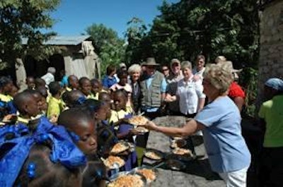 Chicken for Haiti: Missionaries Sherry and Bobby Burnette (back left) are joined by Mike and Rebecca Welch (back right) and Steve Anderson (far back right) as Haitian children are served plates of cooked chicken on rice.