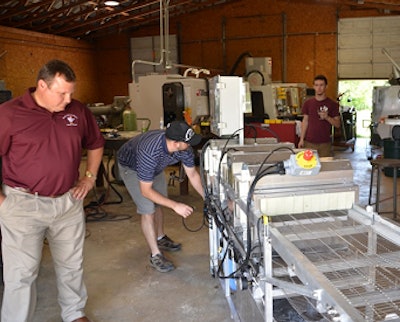 Texas A&M AgriLife Extension Service photo by Robert Burns | Dr. Craig Coufal, left, a Texas A&M AgriLife Extension Service poultry specialist, examines the second-generation egg-sanitizing machine built from his design by a local College Station fabricator.