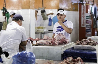 A butcher at a meat counter in Mercado Municipal Adolfo Lisboa in Manaus, Brazil | photo by Frazao | BigStockPhoto