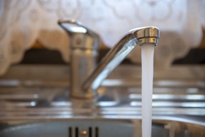 Sink with a tap in a kitchen. Kitchen faucet with running water.