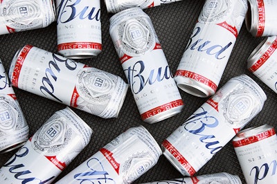 KHARKIV, UKRAINE - AUGUST 1, 2021: Many Cans of Budweiser Lager Alcohol Beer lies on grey background. Budweiser is Brand from Anheuser-Busch Inbev most popular in America