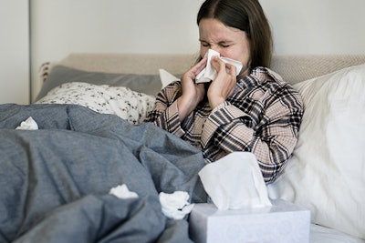 Sick woman sneezing in bed