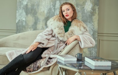 Gorgeous blonde woman in an expensive mink and lynx fur coat posing in an apartment with a classic luxury interior. Fashion shot. Luxury lifestyle.