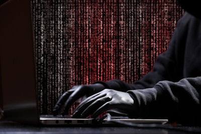 International hacker in black pullover and black mask trying to hack government on a black and red background. Cyber crime . Cyber security.