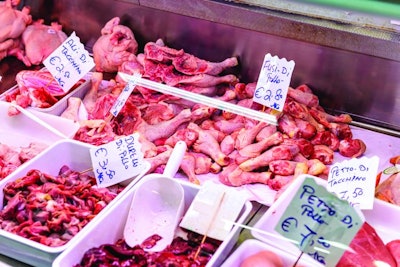 Chicken meat chunks parts on retail display store shop in butchers area in fridge refrigerated with price tag label