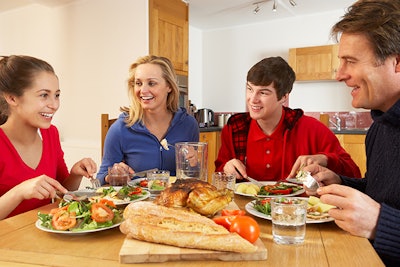 Teenage Family Eating Lunch Together In Kitchen