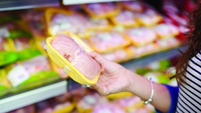 meat in food store . Woman choosing packed fresh chicken meat in supermarket .