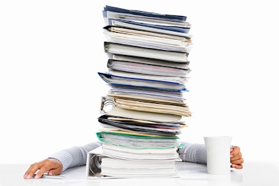 Sleeping worker behind high pile of paperwork isolated in white background