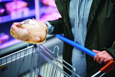 Close-up of woman buying chicken meat from refrigerated section at supermarket.