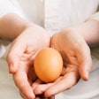 Hands Holding Brown Organic Egg